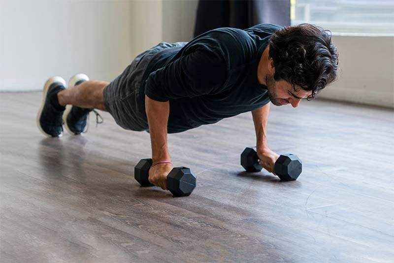 man doing pushup holding dumbbells